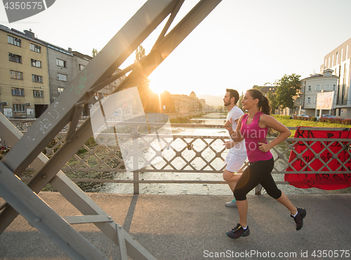 Image of young couple jogging across the bridge in the city