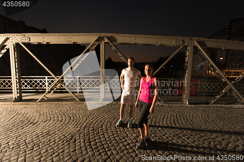 Image of couple jogging across the bridge in the city