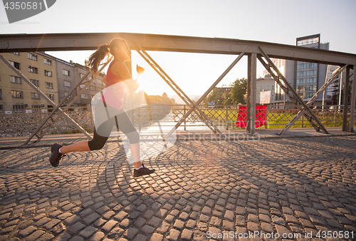 Image of woman jogging across the bridge at sunny morning