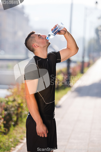 Image of man drinking water from a bottle after jogging