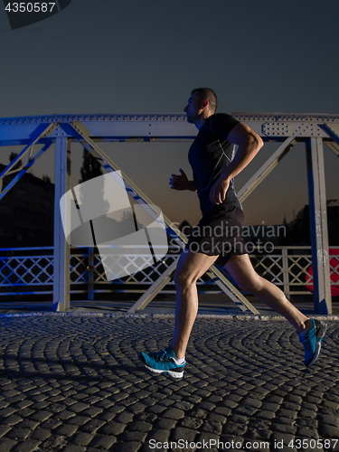 Image of man jogging across the bridge in the city