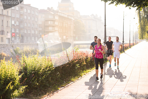 Image of group of young people jogging in the city