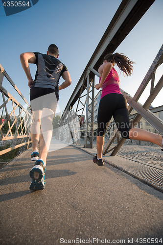 Image of young couple jogging across the bridge in the city