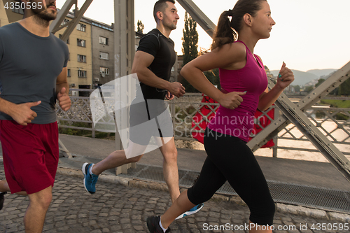Image of group of young people jogging across the bridge