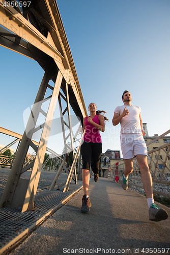 Image of young couple jogging across the bridge in the city