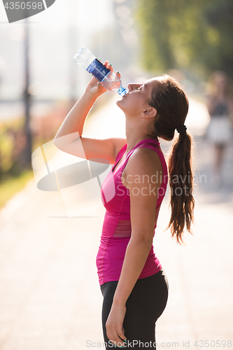 Image of woman drinking water from a bottle after jogging