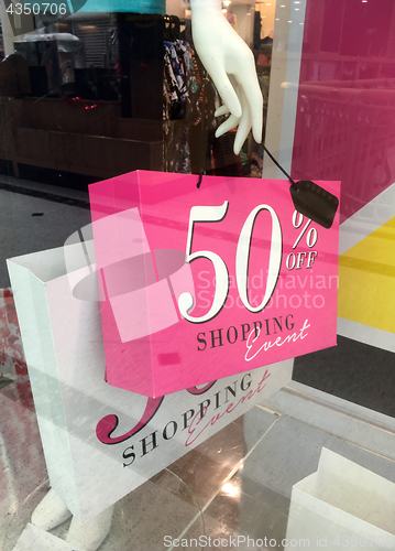 Image of Boutique mannequin holding sale sign on shopping bag
