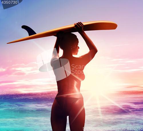 Image of silhouette of surfer with surfboard at sunrise