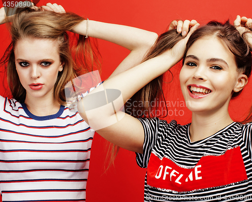 Image of two best friends teenage girls together having fun, posing emotional on red background, besties happy smiling, lifestyle people concept close up