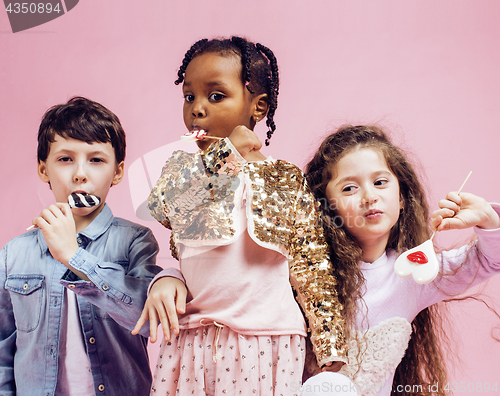 Image of lifestyle people concept: diverse nation children playing together, caucasian boy with african little girl holding candy happy smiling 