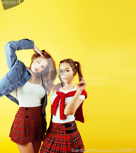Image of lifestyle people concept: two pretty young school teenage girls having fun happy smiling on yellow background 