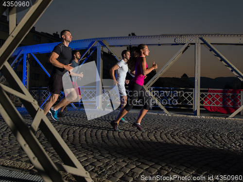 Image of young people jogging across the bridge