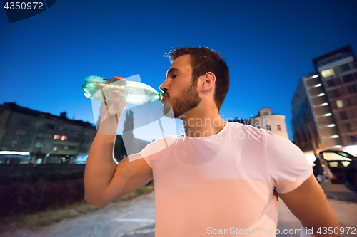 Image of man drinking water after running session