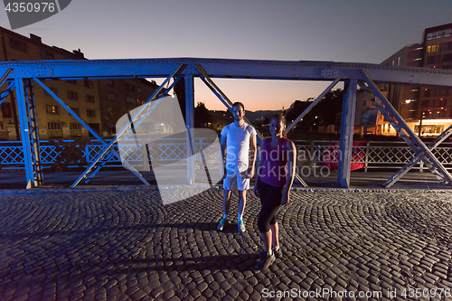 Image of couple jogging across the bridge in the city
