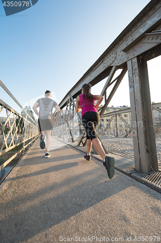 Image of young couple jogging across the bridge in the city
