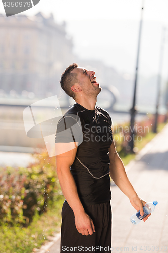 Image of man pouring water from bottle on his head