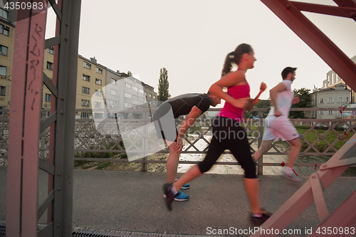 Image of group of young people jogging across the bridge