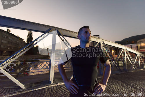 Image of man jogging across the bridge in the city