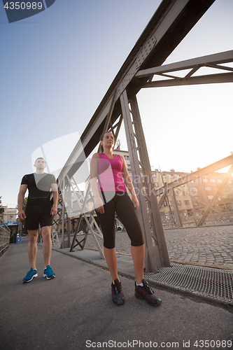 Image of young couple jogging across the bridge in the city