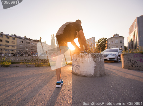 Image of man tying running shoes laces