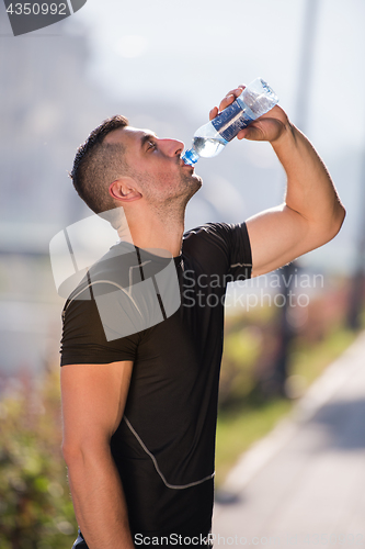 Image of man drinking water from a bottle after jogging