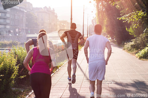 Image of group of young people jogging in the city