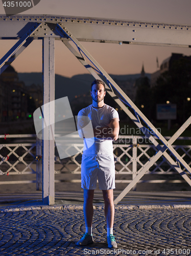 Image of man jogging across the bridge in the city