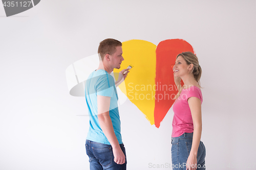 Image of couple are painting a heart on the wall