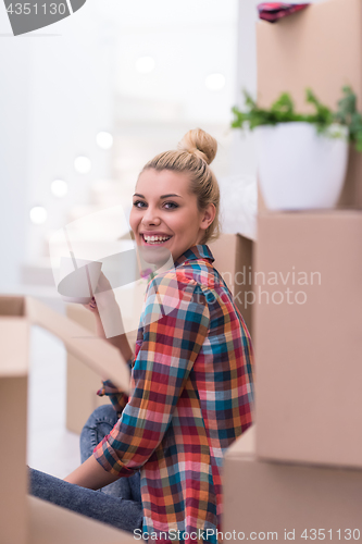 Image of woman with many cardboard boxes sitting on floor