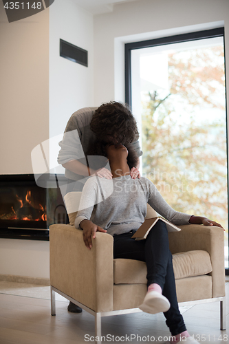 Image of multiethnic couple hugging in front of fireplace