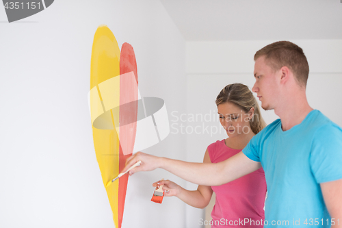 Image of couple are painting a heart on the wall