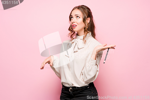 Image of The serious frustrated young beautiful business woman on pink background