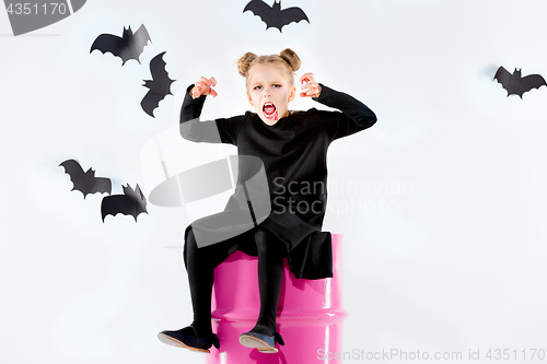 Image of Little girl witch in black dress over magical accessories. Halloween, the studio evening.