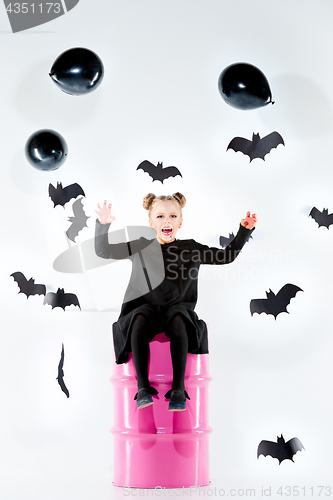 Image of Little girl witch in black dress over magical accessories. Halloween, the studio evening.