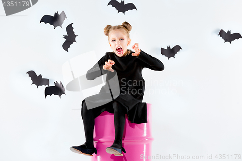 Image of Little girl witch in black dress over magical accessories. Halloween, the studio evening.