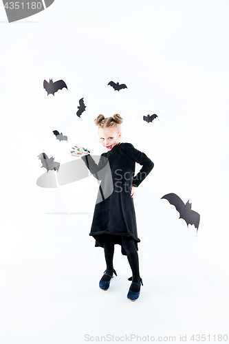 Image of Little girl witch in black dress over magical accessories. Halloween, the studio evening.