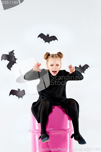 Image of Little girl witch in black dress over magical accessories. Halloween, the studio evening.