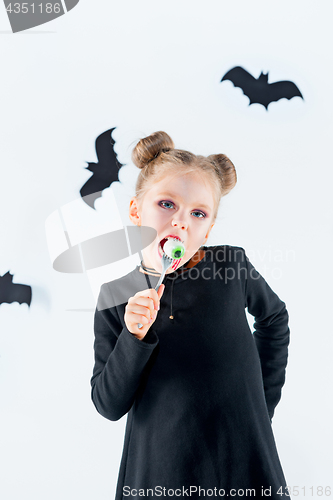 Image of Little girl witch in black dress over magical accessories. Halloween, the studio evening.