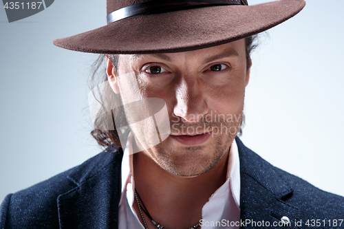 Image of Young man portrait with hat on gray studio background.