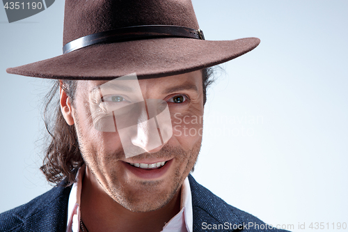 Image of Young man portrait with hat on gray studio background.