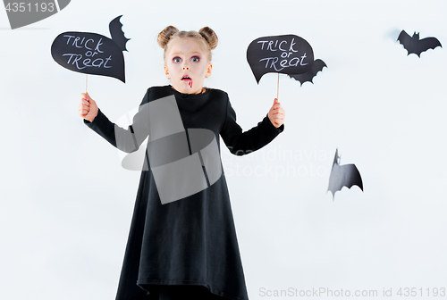 Image of Little girl witch in black dress over magical accessories. Halloween, the studio evening.