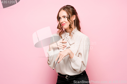 Image of The serious frustrated young beautiful business woman on pink background