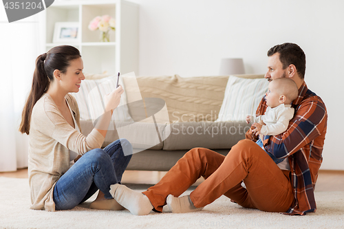 Image of happy family with baby photographing at home