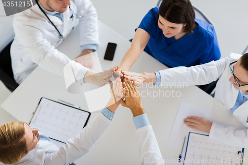 Image of group of doctors making high five at table