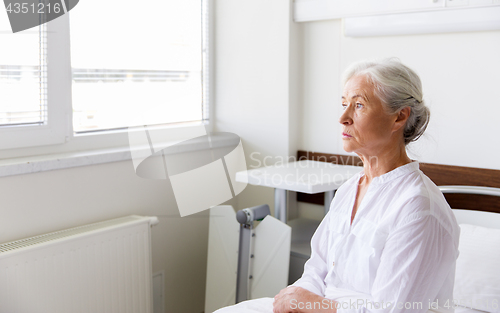 Image of sad senior woman sitting on bed at hospital ward