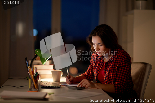 Image of student girl with notebook and calculator at home