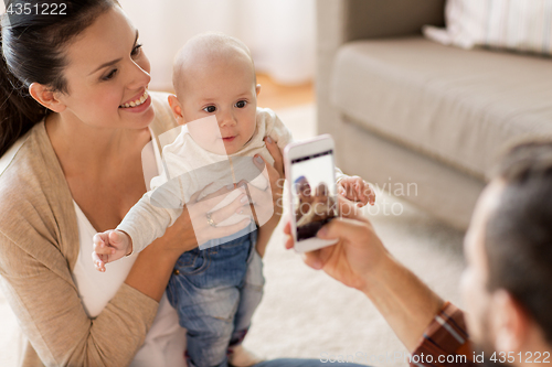 Image of happy family with baby photographing at home