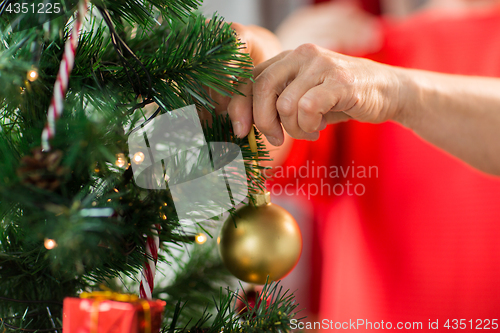 Image of close up of senior woman decorating christmas tree