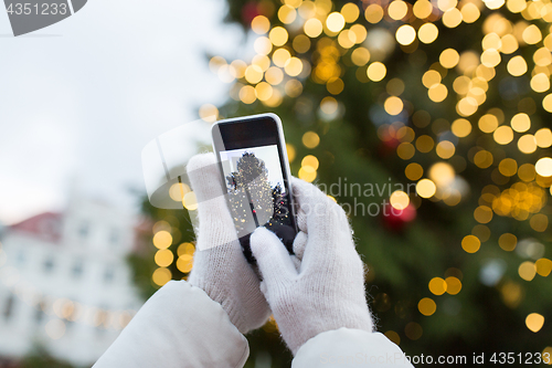 Image of hands with smartphone photographing christmas tree