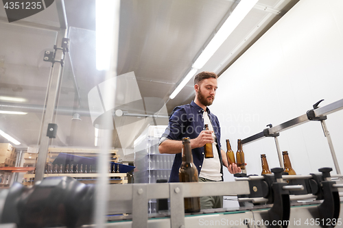 Image of men with bottles on conveyor at craft beer brewery